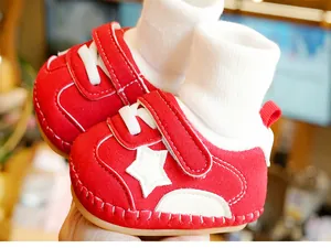 Close-up of red infant walking shoes with soft rubber soles and warm knit ankle cuffs