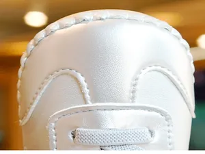 Detail van zilveren babyschoentjes met parelglans en handgestikte randen en veters