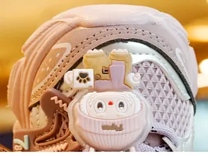 Detail van babyschoen met schattige 3D-cartoon bedeltje en ademende mesh-stof