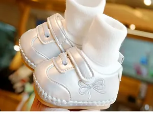 Detail van zilveren babyschoenen met zachte zolen, strikborduurwerk en gebreide kragen