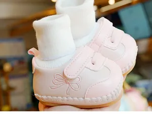 Detail van roze baby loopschoen met strikborduursel en een zachte gebreide sokmanchet