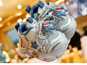 Detail van babysneaker met ademend mesh, ster-logo en schattige dinosaurus decoratie