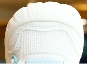 Detailed close-up of white breathable mesh and protective toe cap on toddler walking shoes
