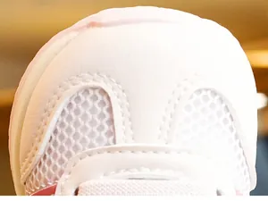 Macro shot of breathable mesh and soft synthetic leather stitching on white baby shoes