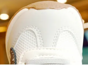Detailed macro view of toddler shoes featuring breathable white mesh and brown rubber toe cap
