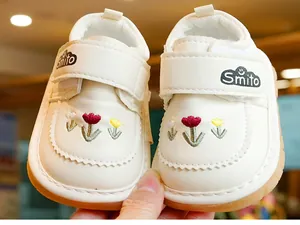 Detail view of white leather toddler shoes with flower embroidery and non-slip rubber sole