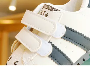 Dettaglio scarpe bimbo in pelle bianca con doppia chiusura a strappo per una calzata sicura