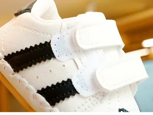 Detail of white infant walking shoes with black jagged stripes and velcro straps