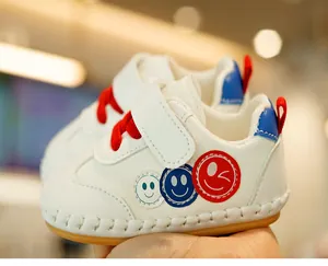 Close-up of baby walking shoes featuring smiley face patches and non-slip rubber soles