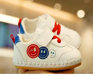 Close-up of white leather baby walker shoes with colorful smiley face patches and non-slip soles