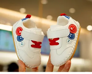 Detail of white infant walking shoes with non-slip soft soles and smiley face patches