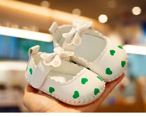 Close-up of baby princess shoes with green hearts, leather bow, and stitched soft sole