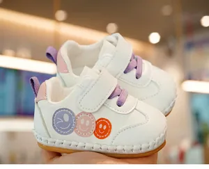 Detail of baby walking shoe with smiley patches, hook-and-loop strap and soft rubber sole