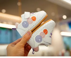 Detail view of white toddler shoes with colorful smiley faces and velcro closure