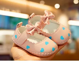 Detail of pink baby Mary Jane shoes featuring blue hearts and a bow with velcro strap