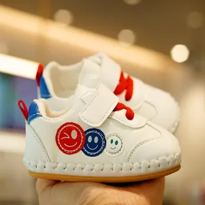 White baby walking shoes with soft rubber soles and smiley face patches