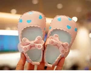 Close-up of pink baby Mary Jane shoes with blue hearts and laser-cut bow detail