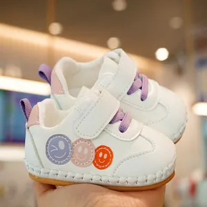 White infant walking shoes with purple laces, smiley face patterns and soft soles
