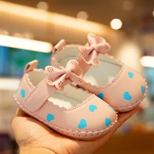 Pink soft-soled baby walker shoes with blue heart patterns and a decorative bow