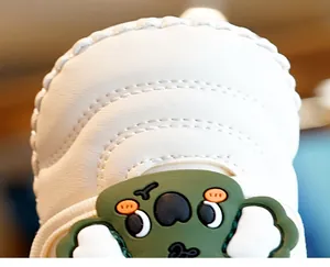 Detail of baby soft-sole shoe featuring cream leather and cute green koala patch