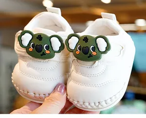 Close-up of white baby walker shoe with cute green koala silicone decor and velcro strap