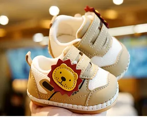 Detail van babyschoentjes met ademend mesh en schattige leeuwen-cartoon decoratie op de zijkant