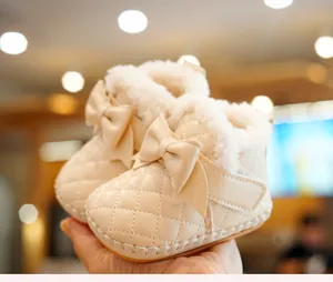 Detail of baby winter boots with fleece lining and large bow on soft cream leather