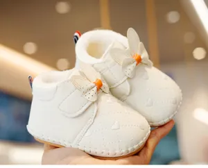 Detail of white infant walking shoes featuring heart embroidery and rabbit ear bows