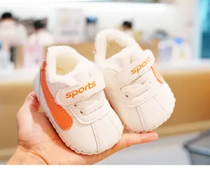 Detaillierte Nahaufnahme warmer Baby-Lauflernschuhe mit orangefarbenen Streifen und Plüsch