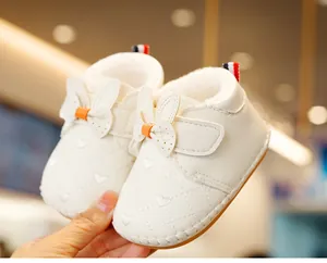 Close-up of white baby shoes featuring quilted heart embroidery and cute rabbit ear bows