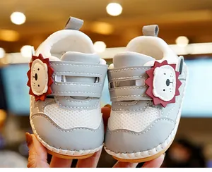 Detail van babyschoentjes met leeuwenstripfiguur en ademend mesh-materiaal voor baby's