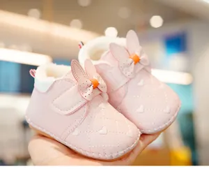 Detail of pink baby walking shoe featuring rabbit ears bow and warm fleece lining