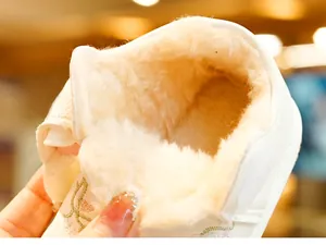 Detail of plush faux fur lining and embroidered edge on a white winter baby shoe