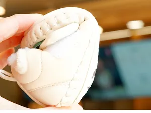 Close-up of soft beige baby shoes being bent to show high sole flexibility and warm lining