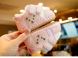 Close-up of pink baby winter boots with warm plush lining and cute bear embroidery