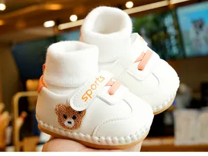 Detail of white baby walking shoe with brown bear embroidery and non-slip rubber sole