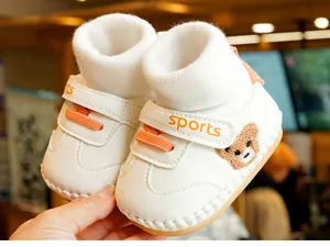Detail of baby soft-sole shoes with bear embroidery, orange laces, and knit sock cuff