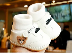 Close-up of white baby walker shoe with cute brown bear embroidery and soft rubber sole