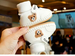 Detail of white baby walking shoe with cute brown bear embroidery and velcro strap