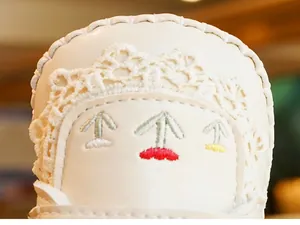 Detail shot of white baby walker shoe featuring colorful embroidery and delicate lace trim