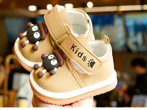 Close-up of khaki toddler walking shoes with cartoon charms and non-slip rubber soles
