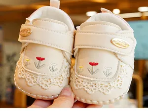 Detail of beige baby walking shoes with floral embroidery and delicate lace trim