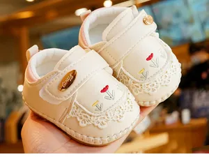 Detail of baby walking shoes with floral embroidery, lace edges and Velcro strap