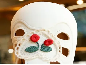 Detailed close-up of cherry embroidery and lace heart on cream baby summer sandals