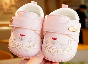 Close-up of soft pink baby walker shoes with delicate lace trim and floral embroidery