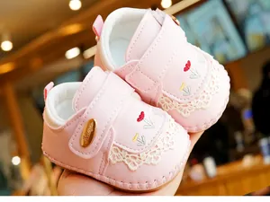 Detailed close-up of pink baby walker shoes with tulip embroidery and lace trim