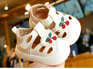 Detailed view of baby walking sandals with cherry embroidery and heart lace patches