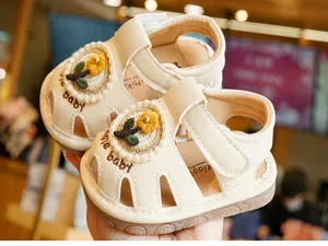 Dettaglio di sandali beige per bambini con ricamo a fiori gialli e design traspirante
