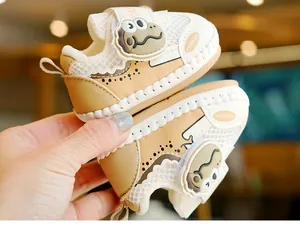 Close-up of baby walking shoe featuring breathable mesh and cute dinosaur velcro strap