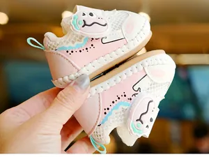 Detail of pink baby walking shoe featuring mesh fabric and a 3D cartoon dinosaur patch